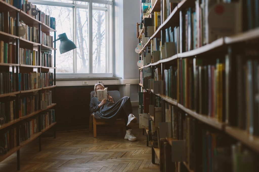Woman reading among bookshelves